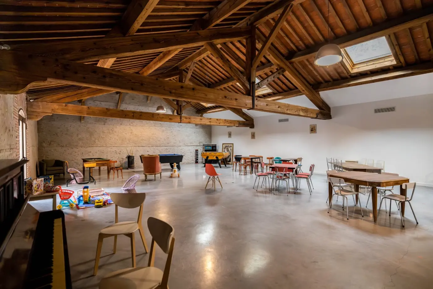 Salle de 200 m² avec charpente en bois, photographiée avec du mobilier