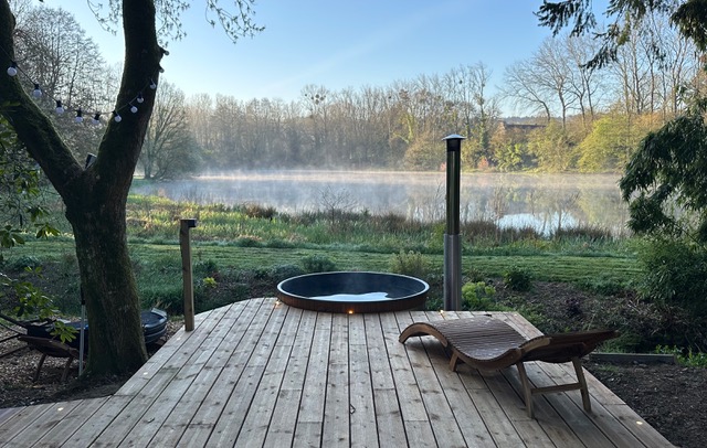 Nordisches Bad aus Holz gegenüber dem Teich im morgendlichen Nebel