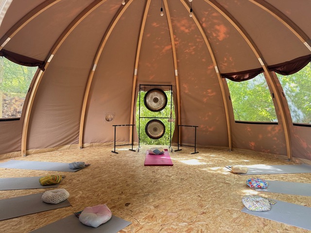Innenraum des Kuppelbaus mit Yogamatten, Kissen und Gongs